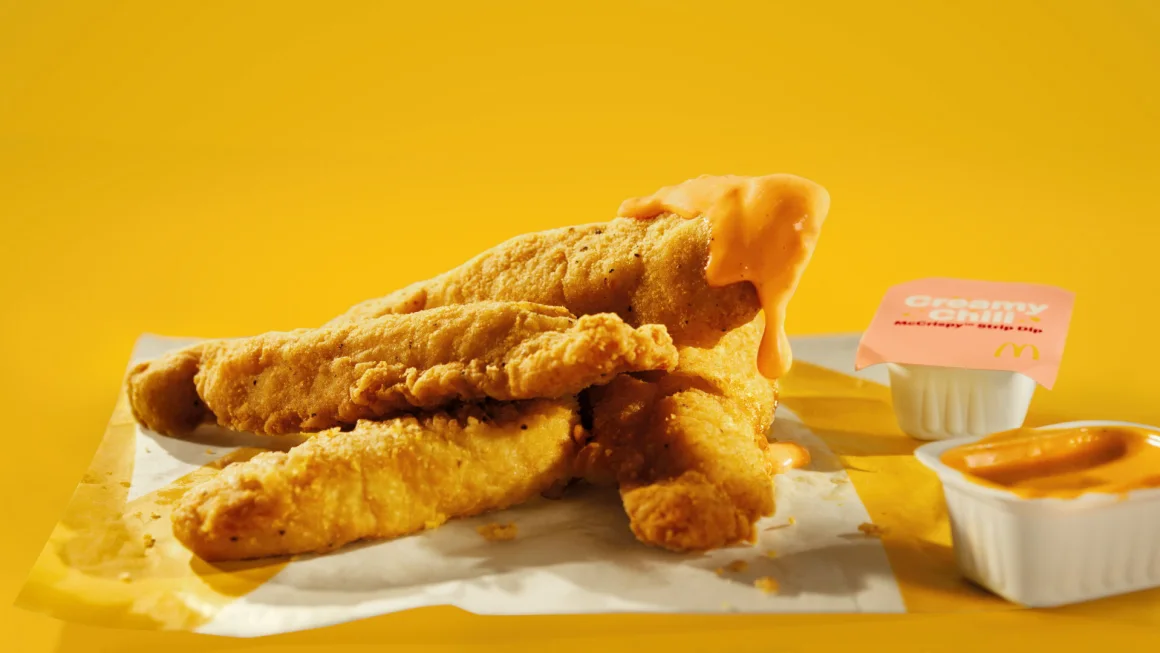 Close-up of McDonald’s crispy chicken strips with dipping sauces, announcing their 2025 return